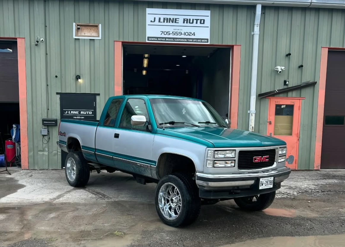 Lifted two tone teal and silver GMC pickup outside the shop