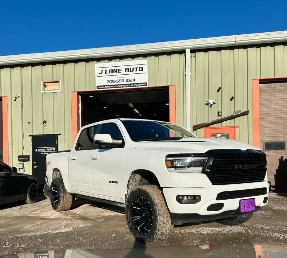 White Ram 1500 with a lift kit and new wheels outside the shop